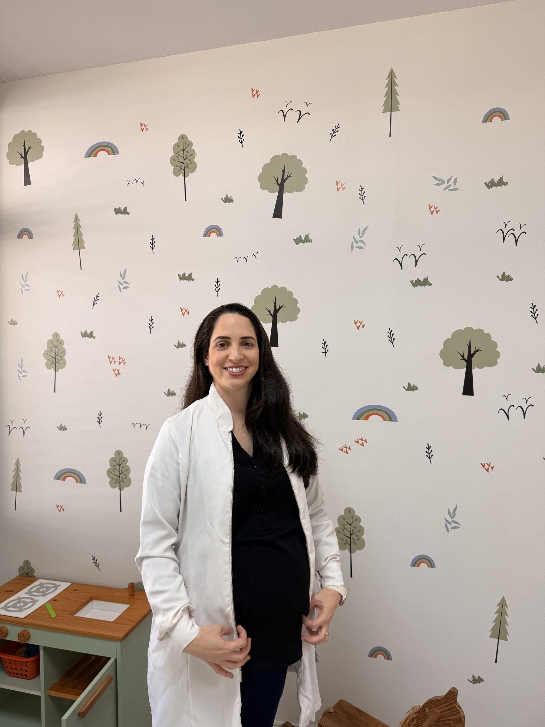 Paula sorrindo na sala infantil do consultório